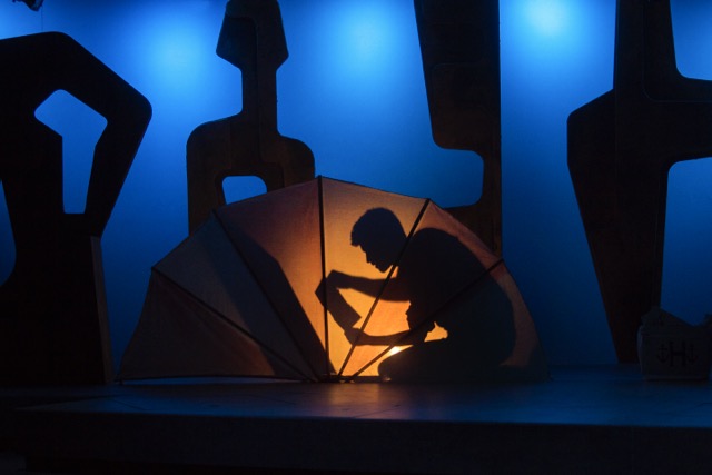 there is a silhouette of a person holding an umbrella on a stage